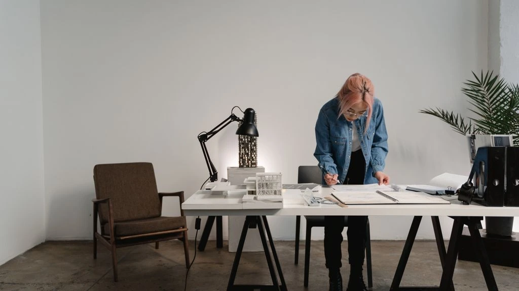 An empty architect's studio at dawn, lit by a single warm side lamp.