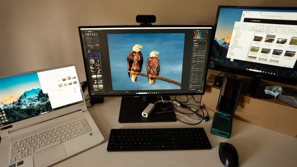 A workstation with a single screen showing a wireframe, ceramic mug, and small plant.